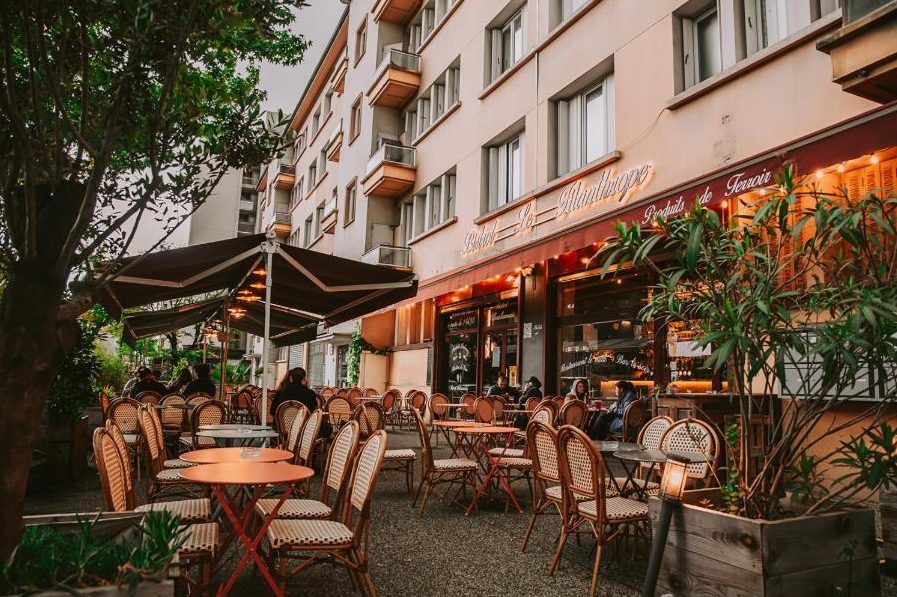 La terrasse du Filanthrope sous les arbres, chaises bistrot et store déployé
